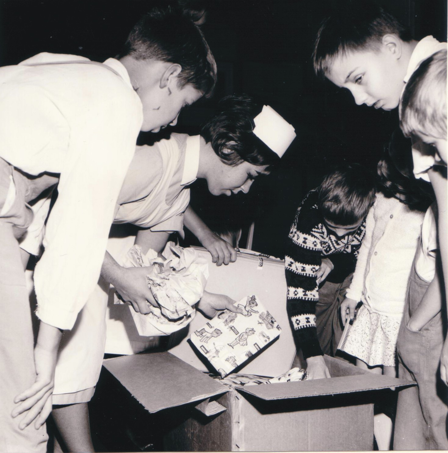 Barn och en sköterska packar upp en låda med presenter från Erik Nilsson
