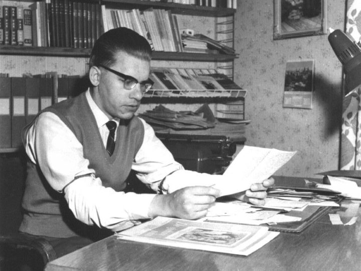 Erik Nilsson, Erikshjälpens grundare, sitter vid ett skrivbord och håller i ett pappersark.