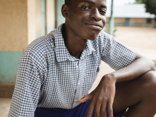 Boy (Lawrence) is sitting in a relaxed cool pose, squatting, looking content.