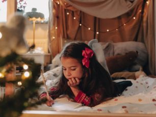 En flicka ligger i sängen och skriver en önskelista till jul.