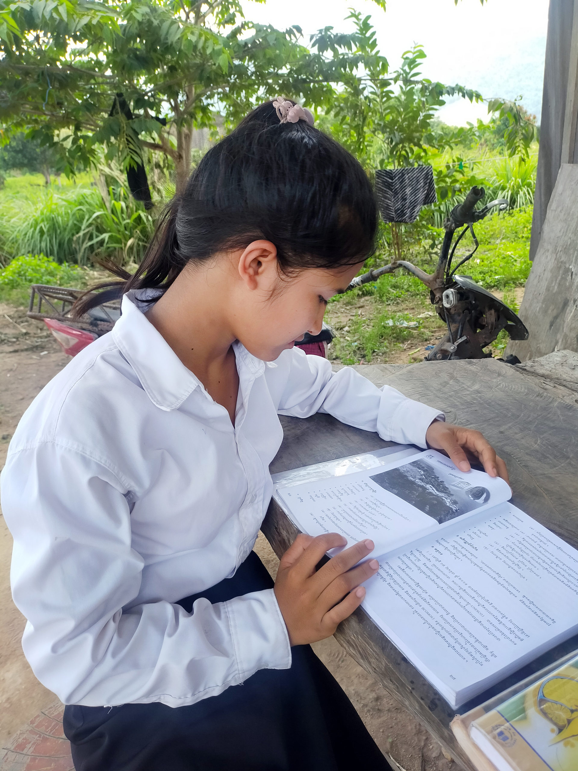 Soeum, en flicka från Kambodja, sitter och läser vid ett bord. Hon syns i profil.