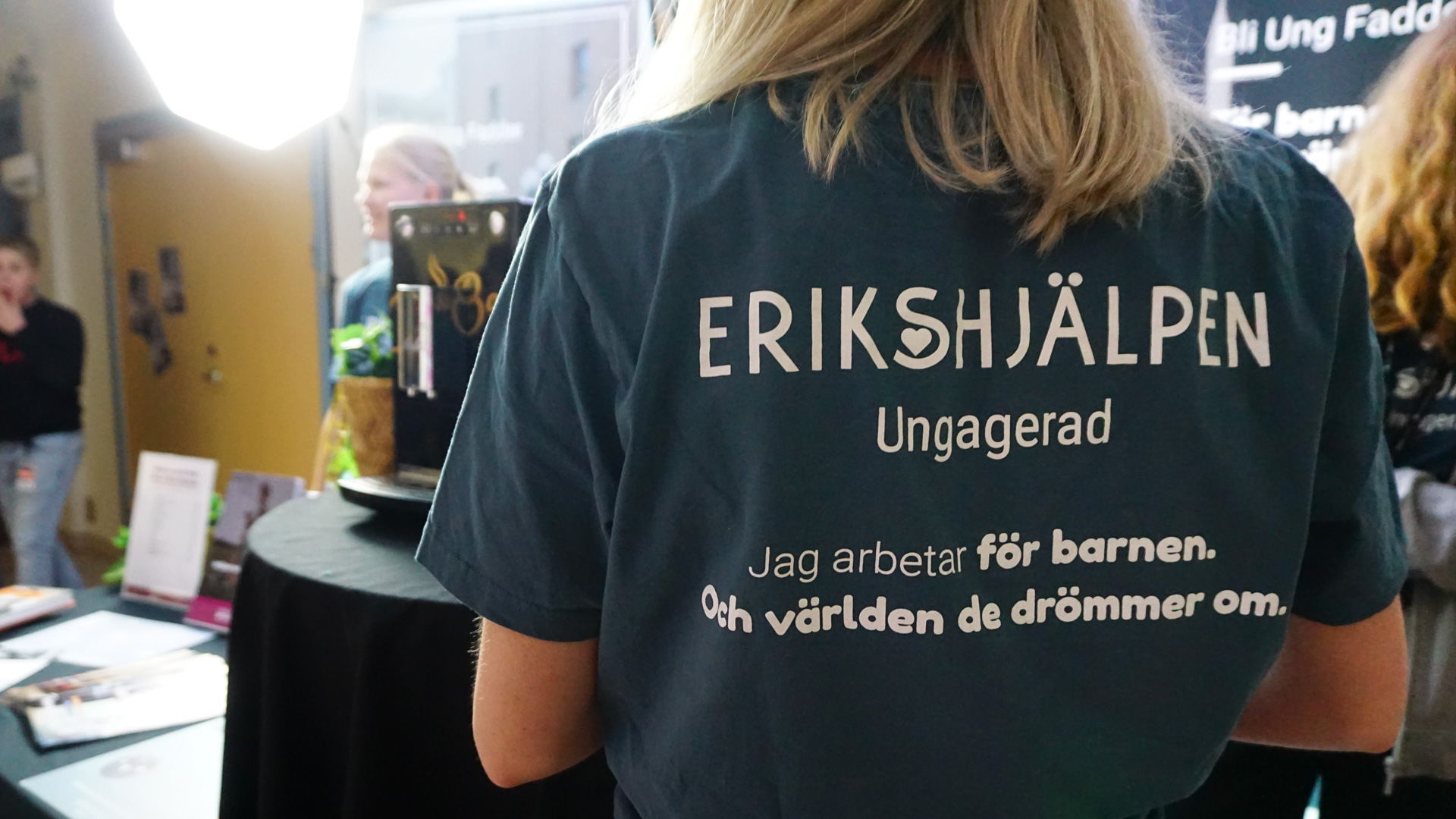 En värvare bakifrån där man ser baksidan av en t-shirt med Erikshjälpen Ungagerad logotyp på.