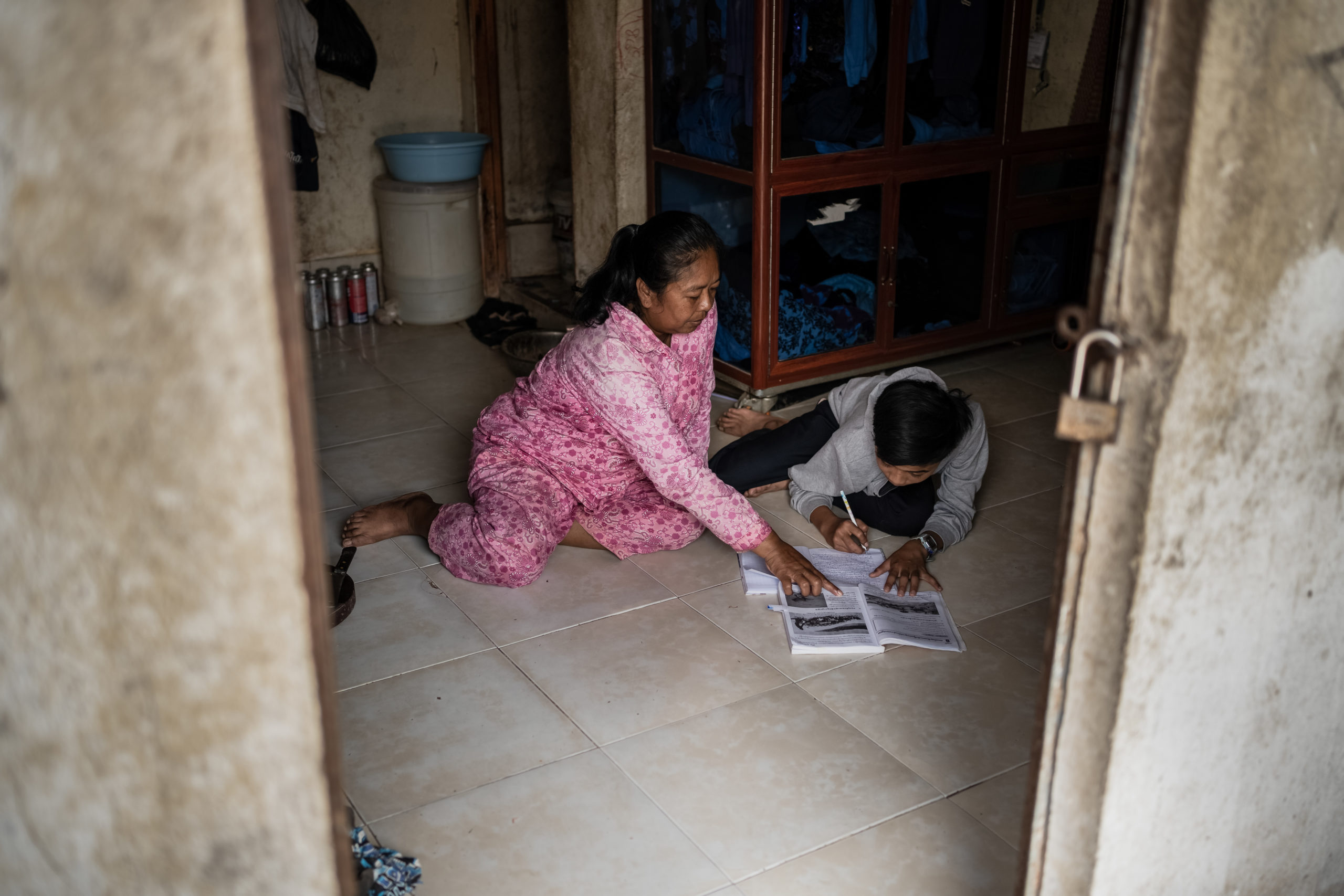 Foto på mamma Sokuntheary som hjälper Sereyvat med läxorna. Foto: Andy Ball/Erikshjälpen