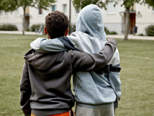Two children hold each other's shoulders.