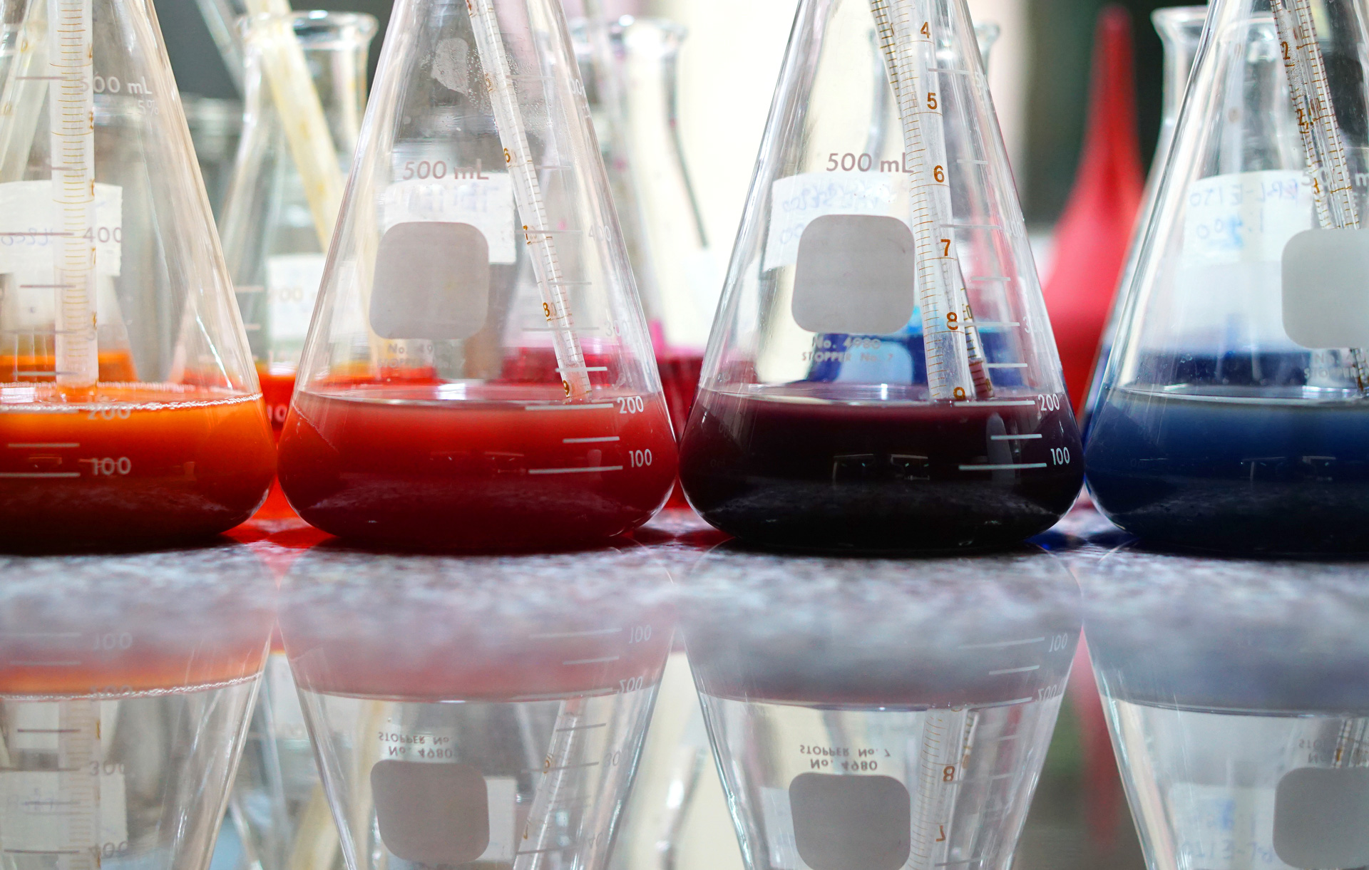 Röda och blåa färgpigment med lösningsmedel i laboratorieglas