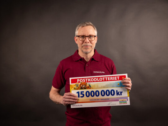 Mattias Ingeson håller i postkodlotteriets check värde 15 miljoner kronor.