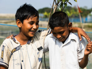 Två killkompisar i Bangladesh som skrattar och kramar om varandra.