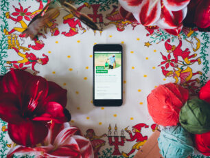 En mobil med ett SMS-julkort på skärmen, ligger bland julamaryllis, trasnystan och bilder av änglar.