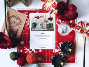 Ett gåvobevis från Erikshjälpen ligger på en julig duk, julamaryllis, en snöglob, levande ljus och stämningsfulla julsaker.