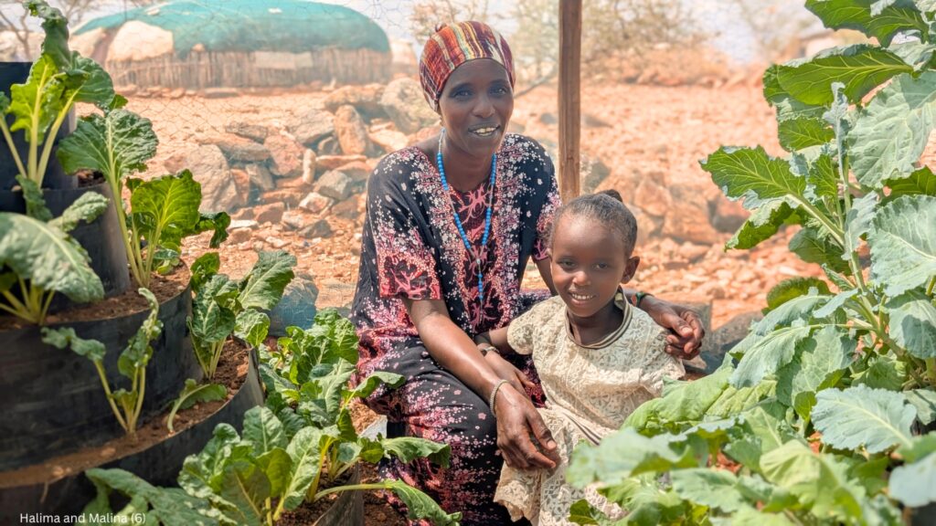 En mamma och hennes barn sitter bland de kägelformade odlingarna i familjens trädgård.