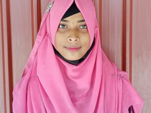 Hiramoni står mot en skolvägg.