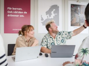 Två personer sitter vid ett bord i ett mötesrum på Erikshjälpen med varsin laptop på bordet.