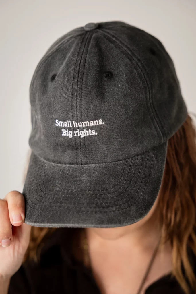 Svart keps med texten "Small humans. Big rights." broderat på framsidan.