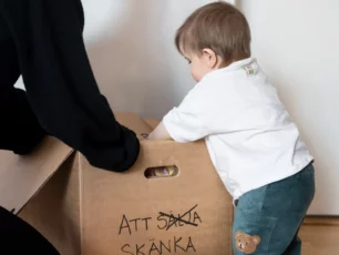 Ett barn hjälper sin mamma att lägga i saker i en kartong med saker att skänka till second hand. 